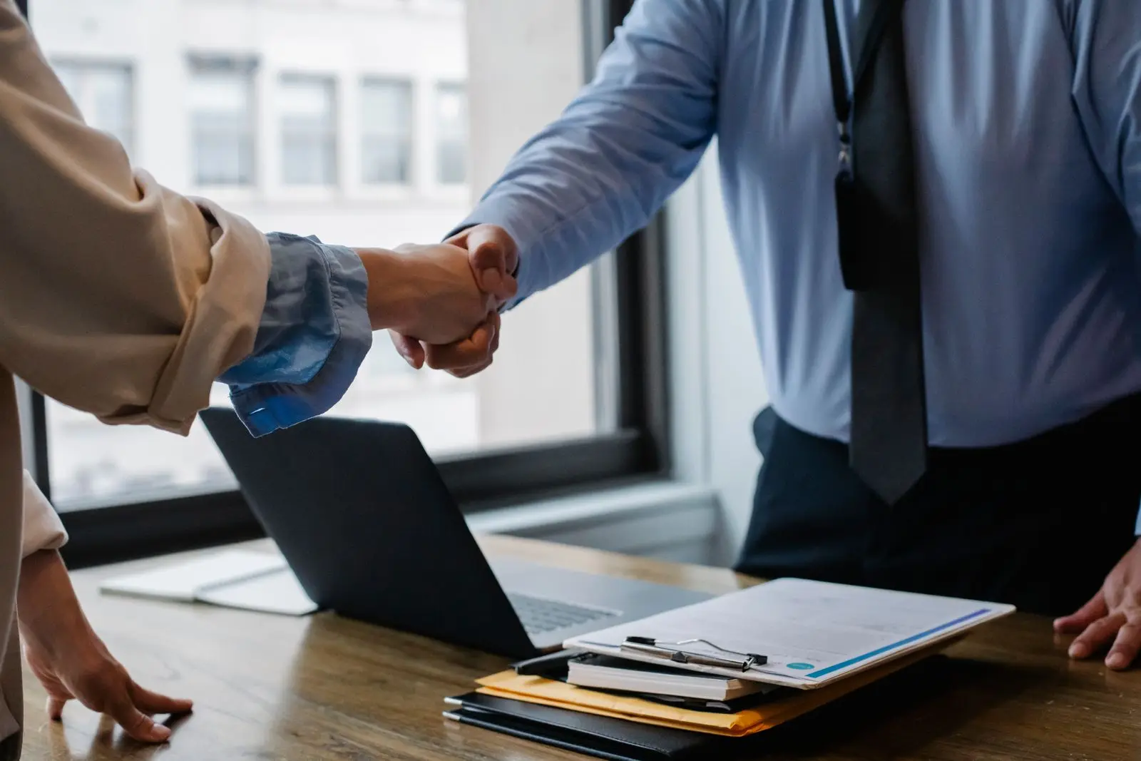 Two professionals shaking hands across an office desk